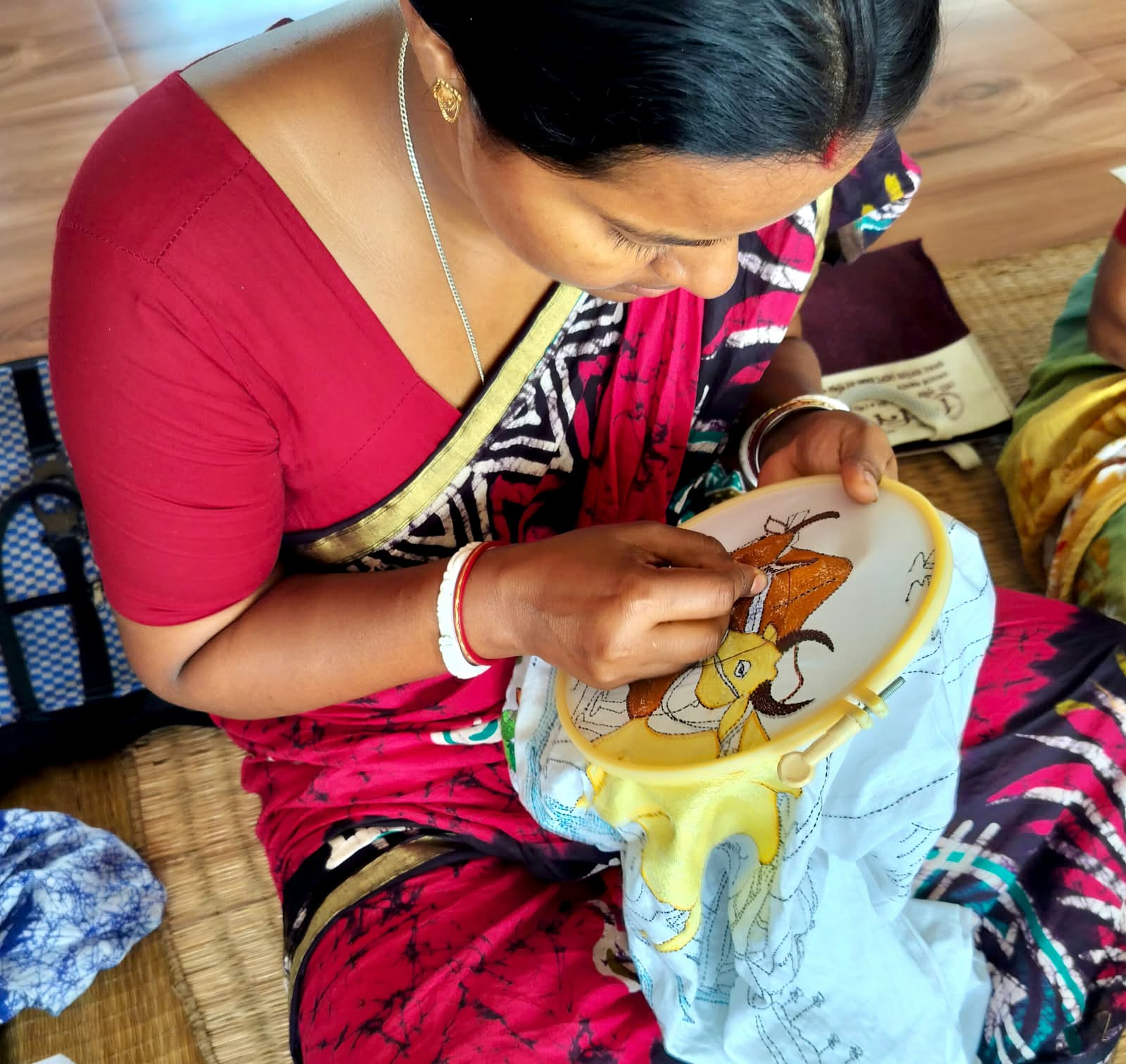 A woman creating detailed embroidery during a Poorbita skills program