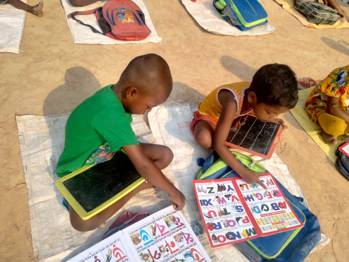 Young children practising letters and drawing in a Poorbita Kishalay class